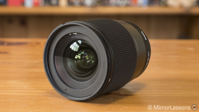 Sigma 16mm f1.4 leaning on a wooden table, with front element visible