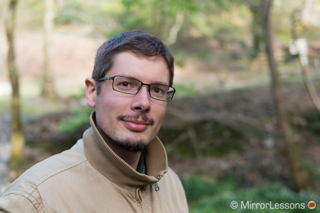 portrait of a young man with short hair and glasses in the woods