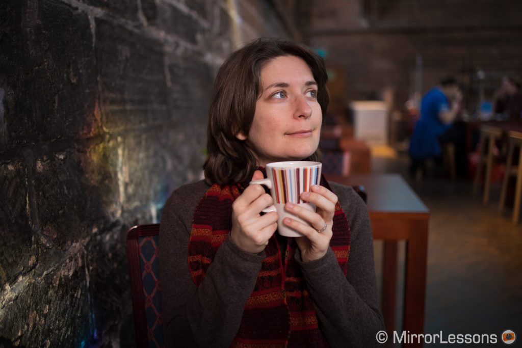 woman holding her cup of tea in a cafe bar, looking on the right