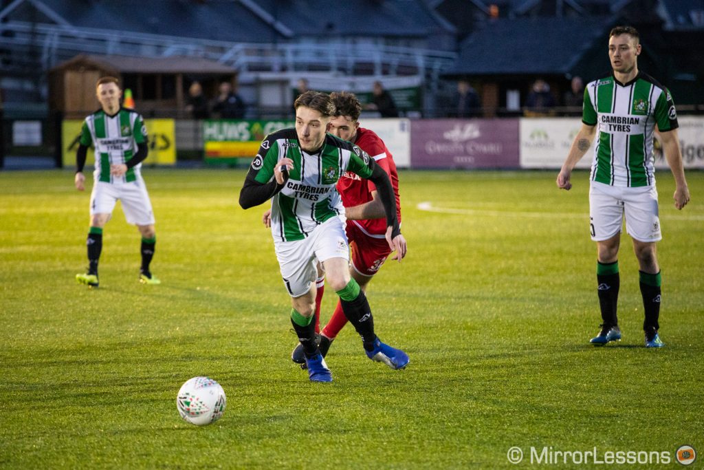 Football players chasing the ball in an evening game.