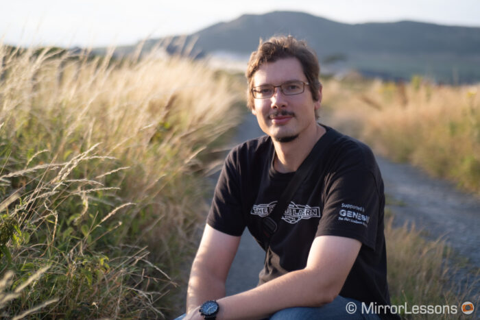 half body portrait of a man taken outdoor near a field with the 55mm 1.4