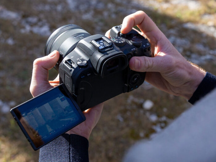 Male hands holding the Canon R6 with the LCD screen opened on the left side