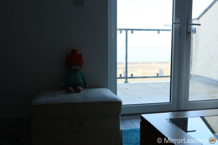 living room with window on the right showing outdoor balcony and sea in the background
