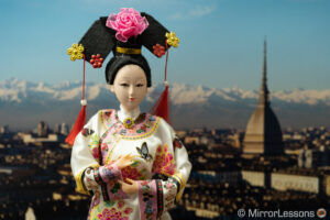 Muñeca japonesa frente a la foto de un panorama de la ciudad al fondo.  La imagen es más brillante que la anterior.