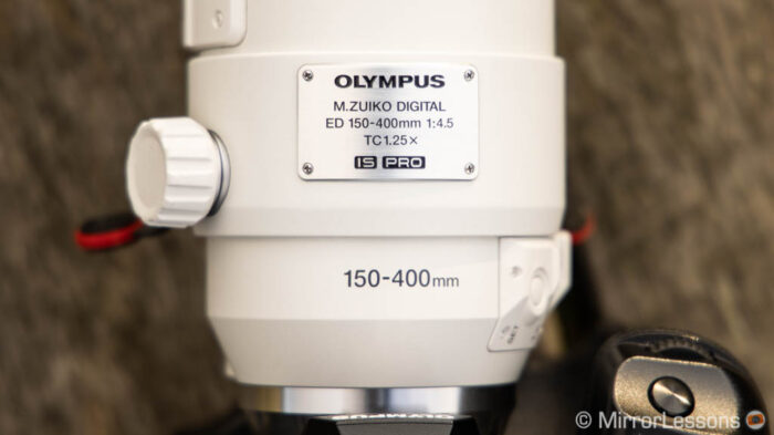 close-up detail of the lens showing the metal plate with full name of the lens: Olympus M.Zuiko Digital ED 150-400mm f/4.5 TC 1.25X IS PRO