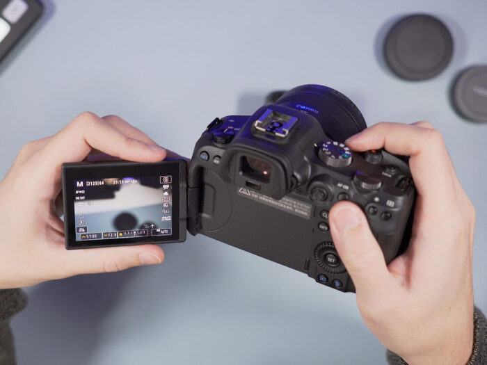 male hands holding the Canon R6 with the LCD screen opened on the side