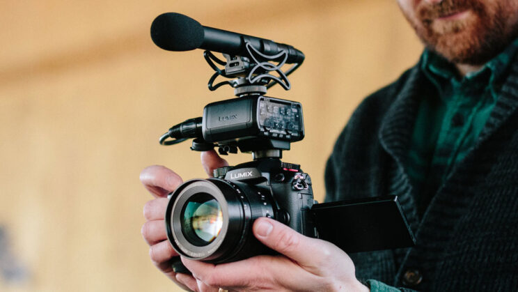 close-up on the GH5 II with XLR microphone mounded on the hot-shoe, held by the hands of a camera operator