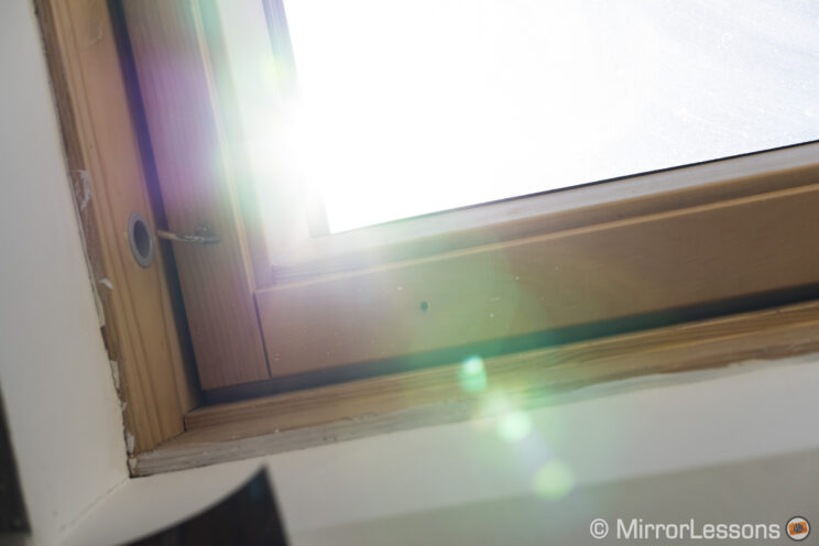 bottom right corner of a roof window with sunlight in the background to show the sensor flare