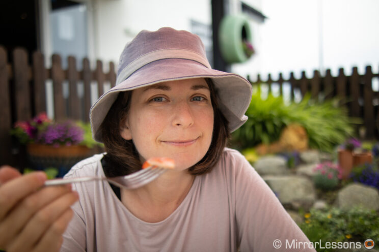 portrait of a lady with hat in a garden cafè, holding a fork with food on it