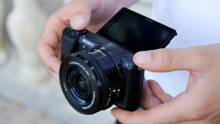 hands holding the Sony A5100 with LCD screen tilted up