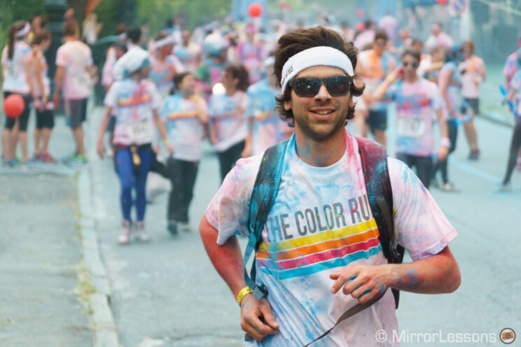 man with sunglasses running at the color run event and covered in coloured powder