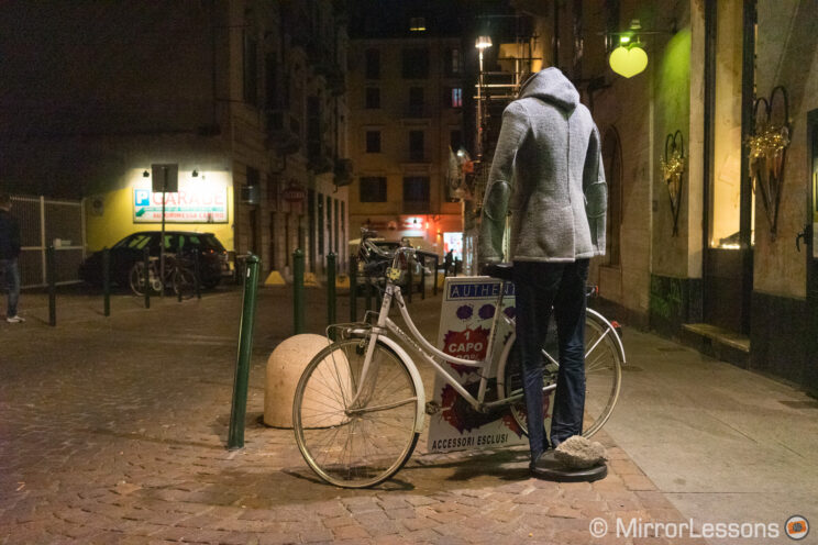 street at night with bike parked on the side and a mannequin next to it