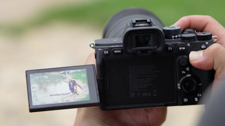 hands holding the A7 IV with the screen opened on the side