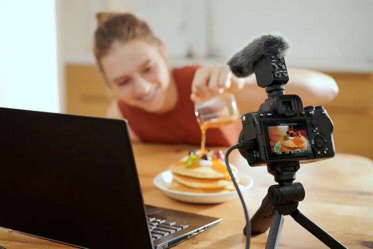 V-logger pouring sauce on pancakes in front of the camera connected to a laptop