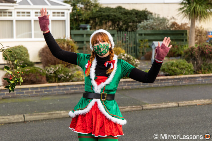 Woman dressed in Christmas clothes dancing and waving at the camera