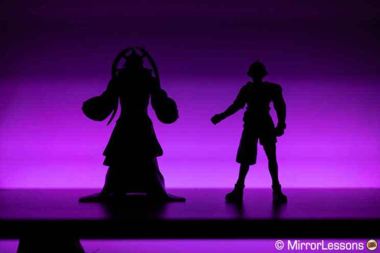 Two action figures silhouette with purple LED light in the background