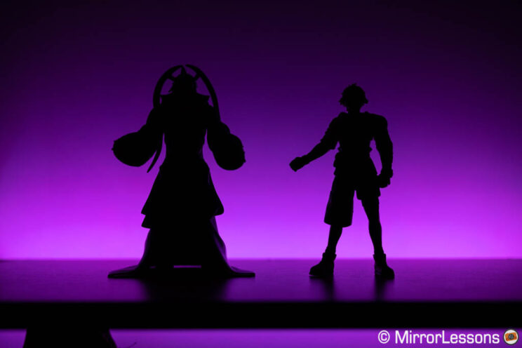 Two action figures silhouette with purple LED light in the background