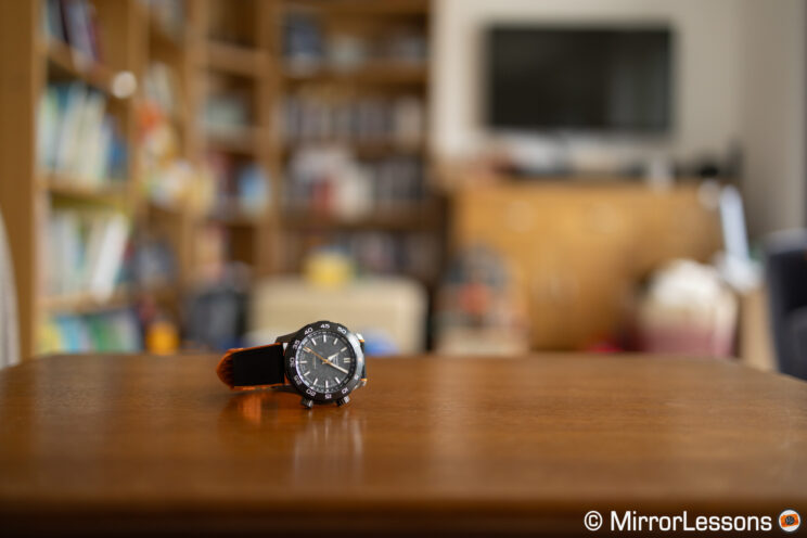 Watch on a table with our of focus bookshelf in the background