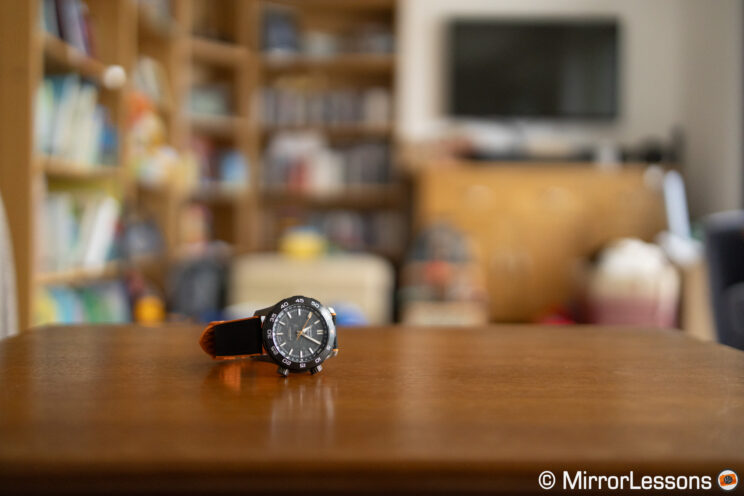 Watch on a table with our of focus bookshelf in the background