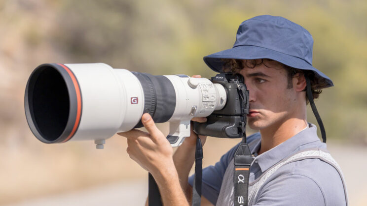 Photographer holding the Sony A9 III with a big telephoto lens.